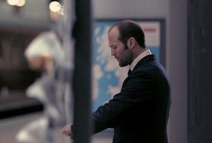 Jason Statham looking at his wristwatch in The Bank Job