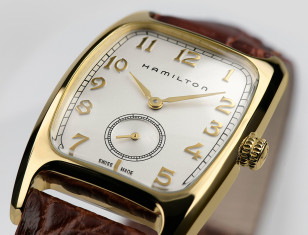 The gold Hamilton Boulton watch with white dial and brown leather strap.